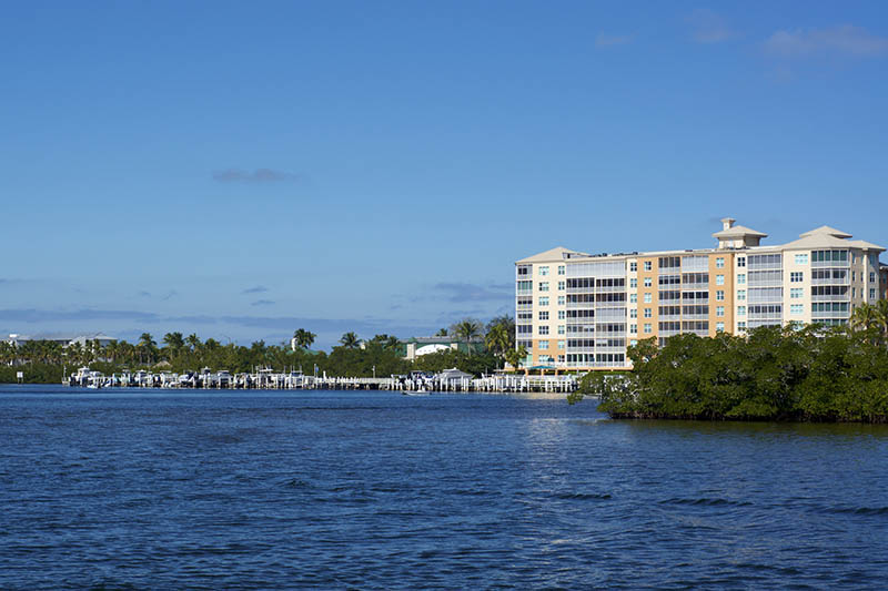 Scenic view of Bonita Springs Florida, looking across canal towards large building and boat docks.