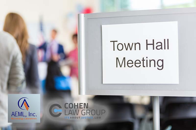 Group of people gather for town hall meeting. A 'Town Hall Meeting' sign is at the entrance of the meeting room. The crowd is blurred in the background.