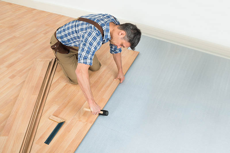 Carpenter Installing New Laminated Wooden Floor At Home