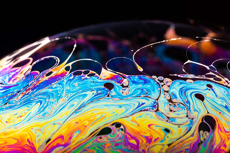 Rainbow soap bubble on a dark background. Close-up of a bubble