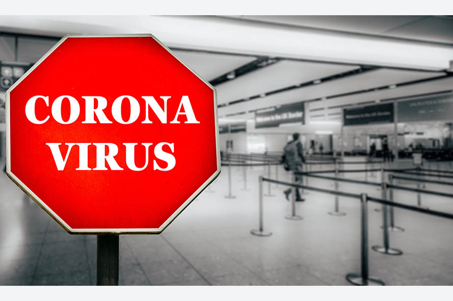 Coronavirus written on stop sign with passengers arriving at passport control within generic airport. The virus, which originated in China is quickly spreading around the world in early 2020
