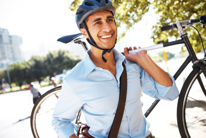 A young businessman carrying his bicycle to work