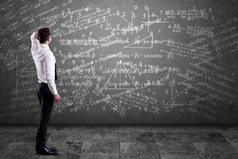Young man looking at mathematical equation on wall. Concept of problem solving.