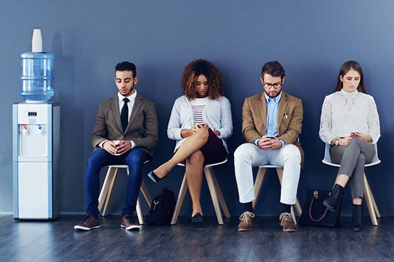 Full length shot of four businesspeople sitting in line for an interview