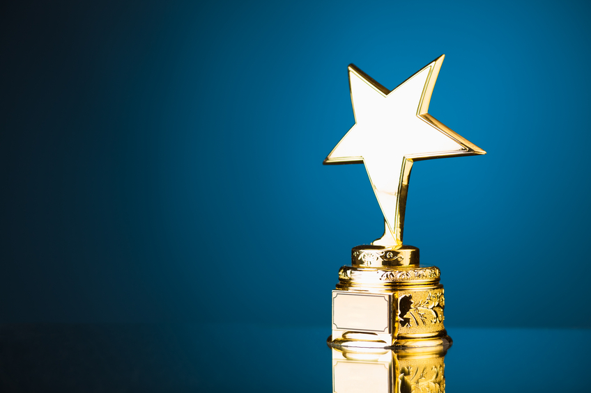 shiny gold star trophy against blue background with copy-space