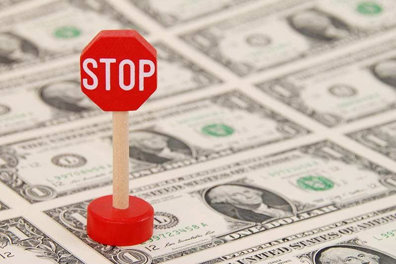 STOP Sign standing on One Dollar Bills - shallow dof