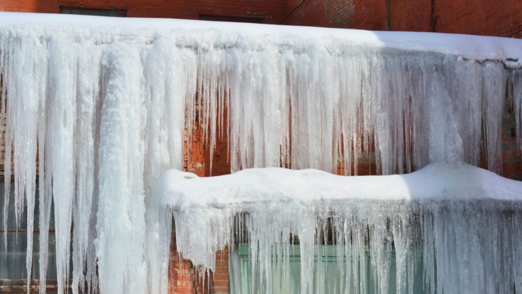 Long, big and dangerous icicles on a brick house roof