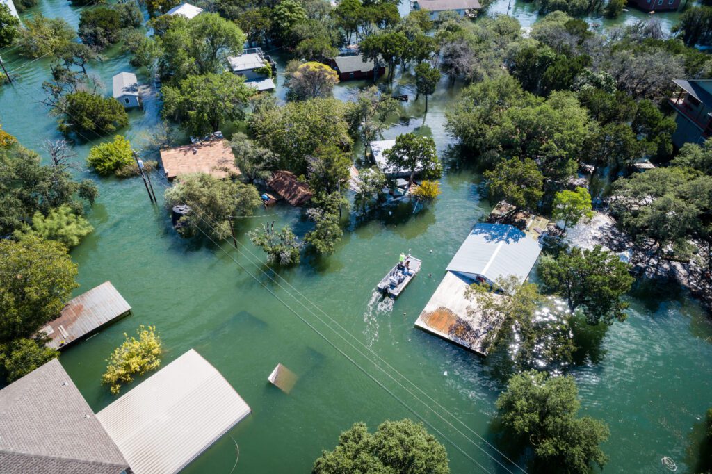 Water Rescue crew on site searching for survivors after dangerous Flooding Aerial drone views high above Flooding caused by Climate Change leaving entire neighborhood underwater and houses completely under water , boat with water rescue searching for people stuck in their flooded homes