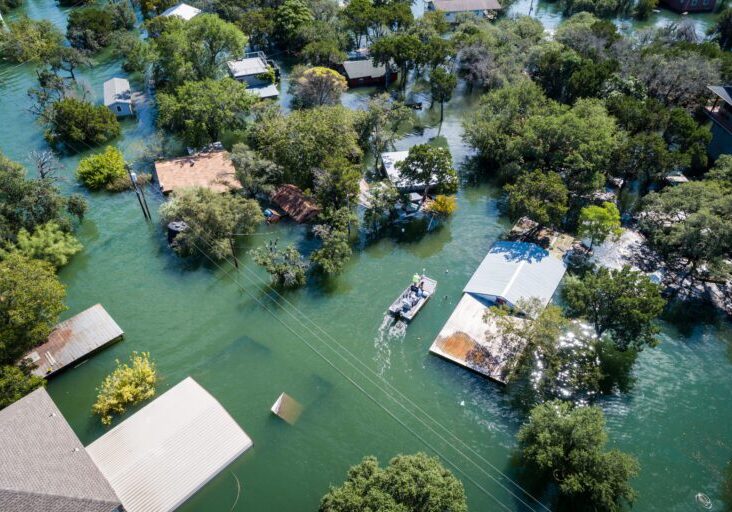Water Rescue crew on site searching for survivors after dangerous Flooding Aerial drone views high above Flooding caused by Climate Change leaving entire neighborhood underwater and houses completely under water , boat with water rescue searching for people stuck in their flooded homes