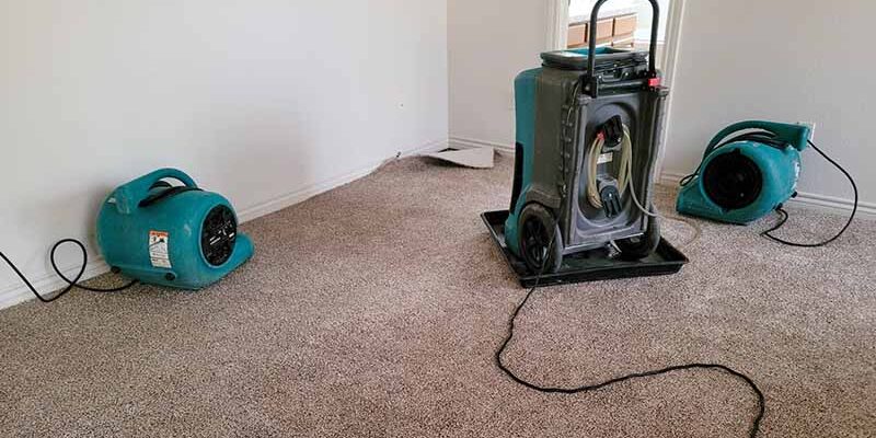 Two air movers and a dehumidifier drying a home.