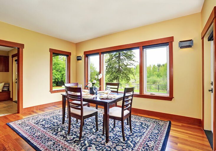 Bright dining room interior design with elegant table setting. Has hardwood floor and nice blue oriental rug.