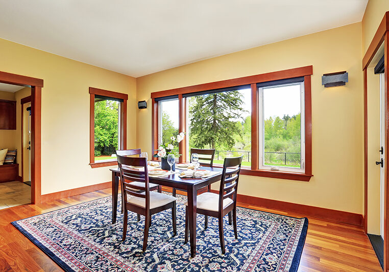 Bright dining room interior design with elegant table setting. Has hardwood floor and nice blue oriental rug.