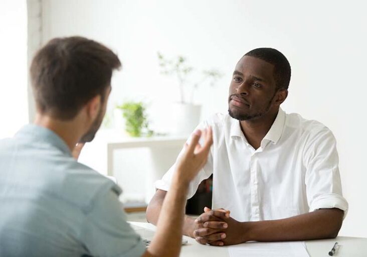 African American employer listening attentively to caucasian job applicant talking at work interview, being friendly and interested to candidate. Concept of recruiting, employment, hiring