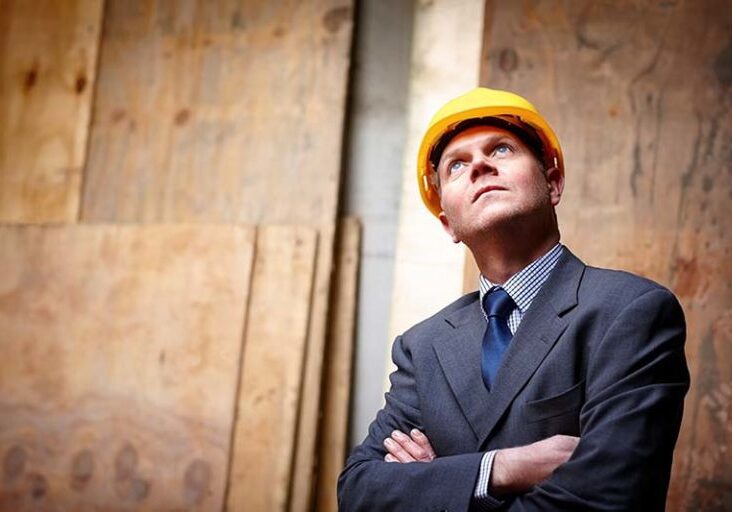 Portrait of mature male engineer looking upwards with his arms crossed at construction site