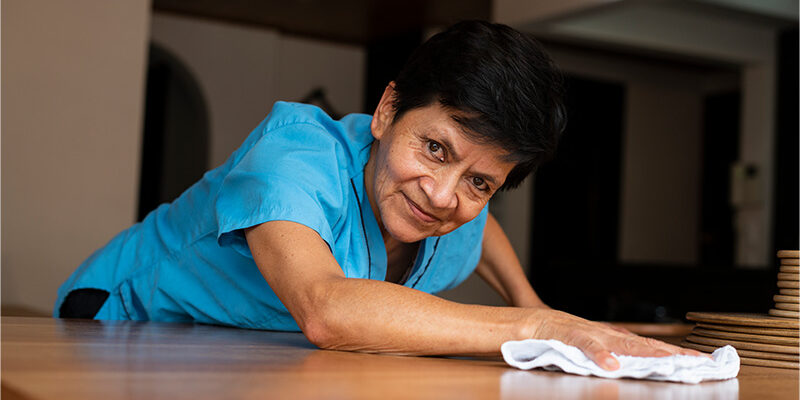 Older Hispanic woman cleaning a table