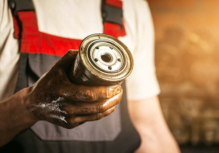 Mechanic. Dirty hands holding oil filter.