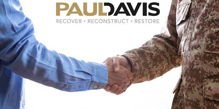 Military person and civilian shaking hands standing on white background