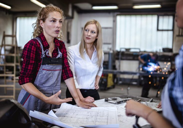 A group of people discussing new plans for construction in the metalshop