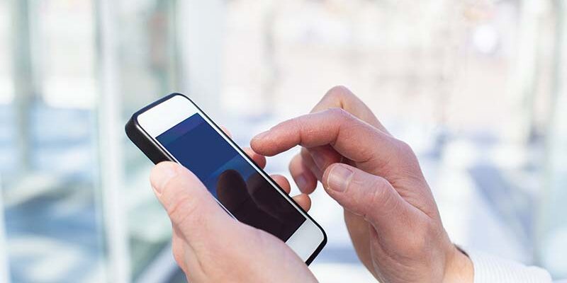 closeup of hands with smartphone in the office, airport or modern train station