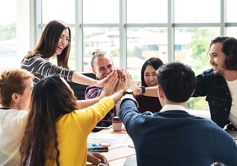 group of young multiethnic diverse people gesture hand high five, laughing and smiling together in brainstorm meeting at office. Casual business with startup teamwork community celebration concept.