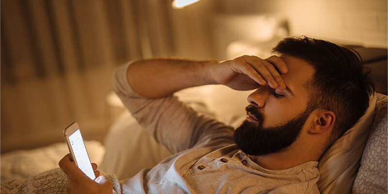 frustrated man reading a text message at night