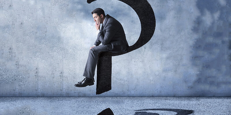 A businessman sits on a floating question mark as he brainstorms about a possible solution.