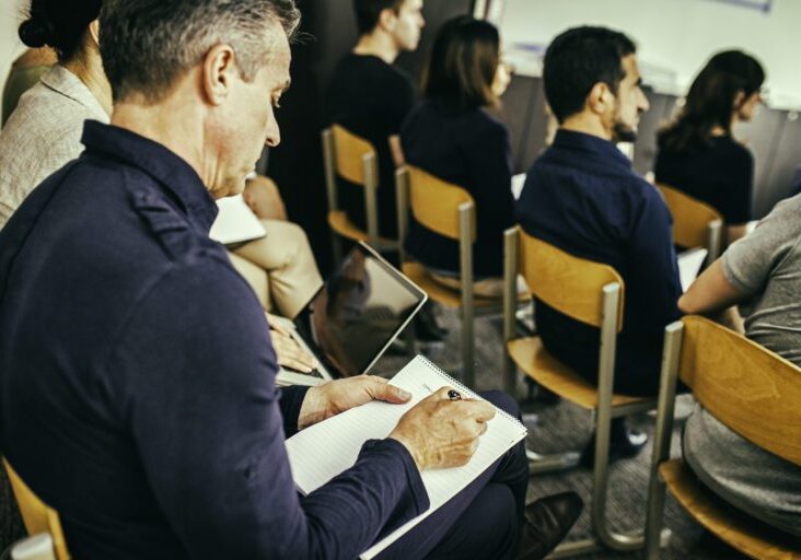 Close up shot of audience in casual clothing listening at seminar.