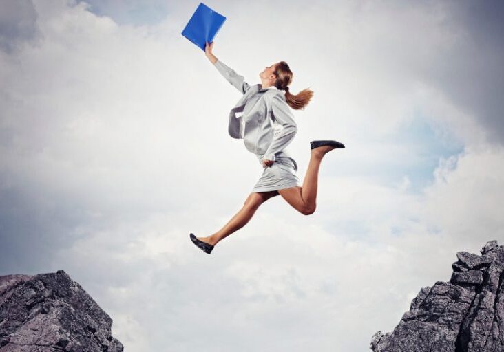 Image of young businesswoman jumping over gap