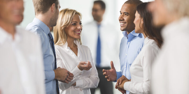 Happy business people standing and talking to each other.