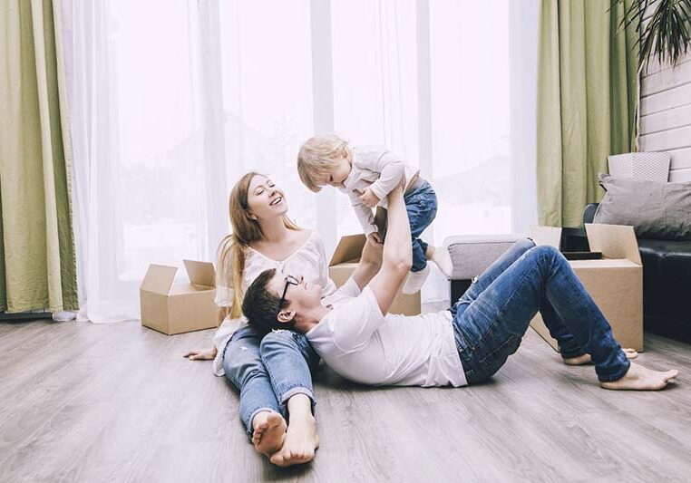 Family together happy young beautiful with a little baby moves with boxes to a new home