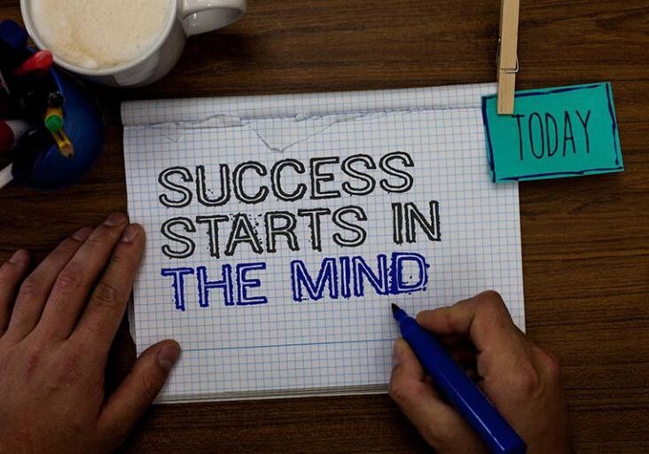 Conceptual hand writing showing Success Starts In The Mind. Business photo showcasing Have positive thoughts accomplish what you want Hand hold pen paper clip written notepad pen case coffee mug