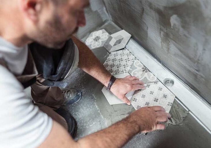 High angle image of male builder installing tiles on the bathroom floor